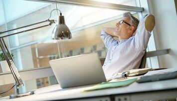 Man leunt achterover aan bureau