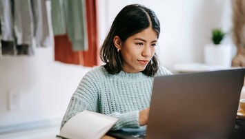Vrouw in blauwe trui achter laptop