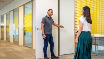 Man laat vrouw voor in kantoorruimte