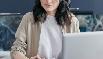 Vrouw met rekenmachine achter laptop